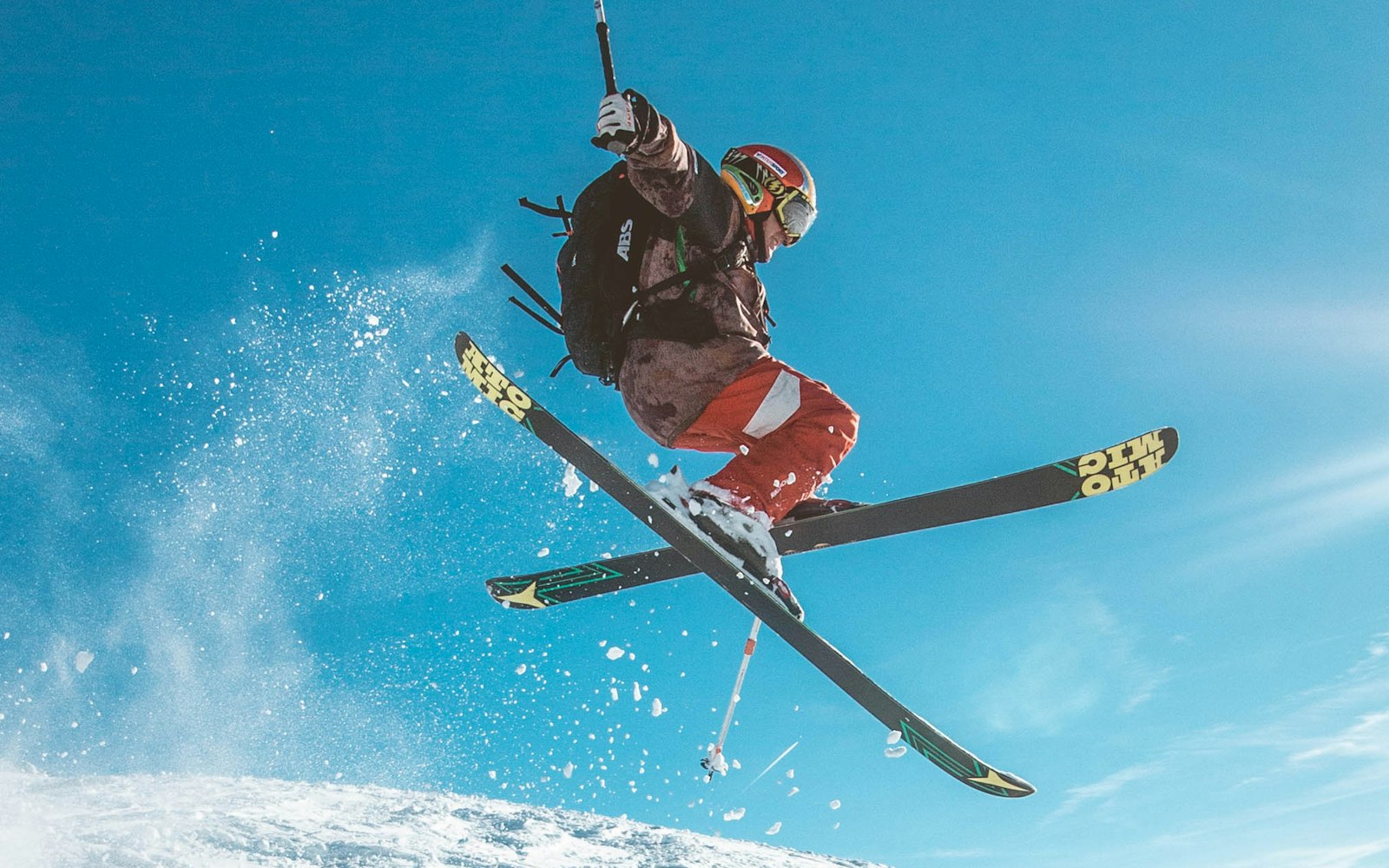 A skier carving down a steep, snow covered alpine slope